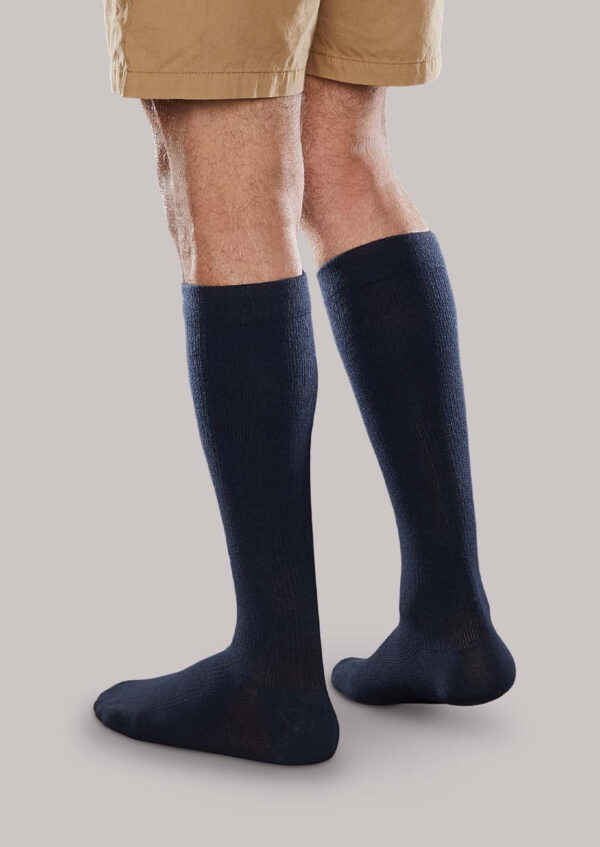 A person wearing Core-Spun 20-30 mmHg dark knee-high compression socks and beige shorts, standing on a plain background.